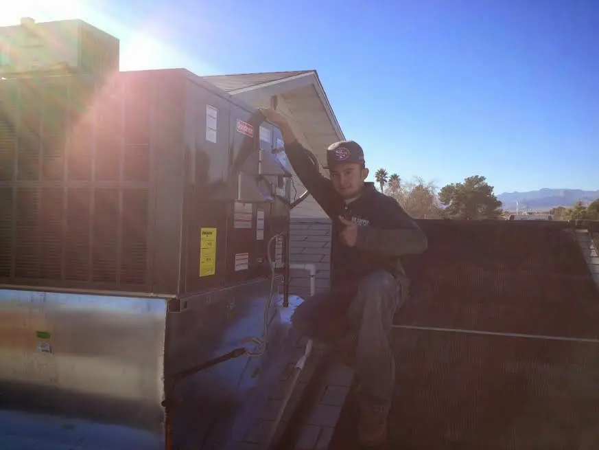 HVAC technician performing AC Tune-Up on a rooftop unit in Zachary